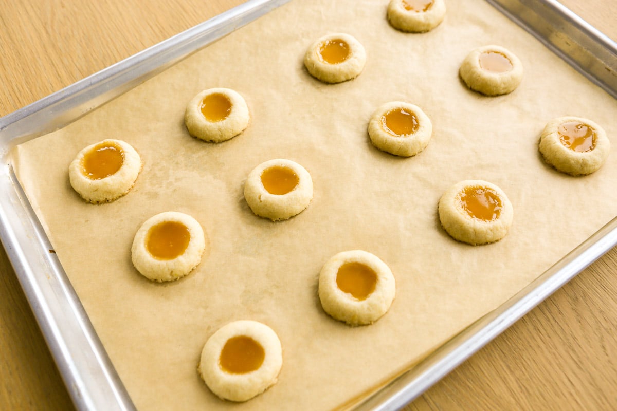 Baked lemon curd cookies set on a parchment lined baking sheet.
