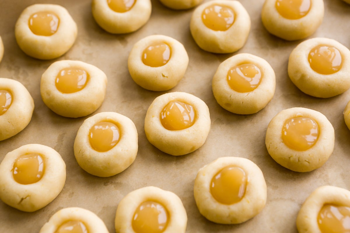Lemon thumbprint cookies, filled with lemon curd, unbaked and set on a parchment-lined baking sheet.