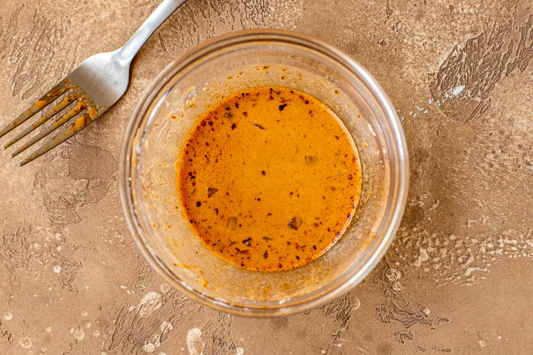A cornstarch slurry made with sauce from the beef stew, in a small clear bowl and a fork set next to it.