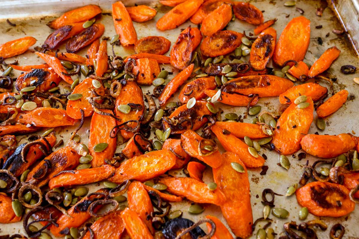 Roasted carrots with crispy fried shallots and pepitas scattered over top.