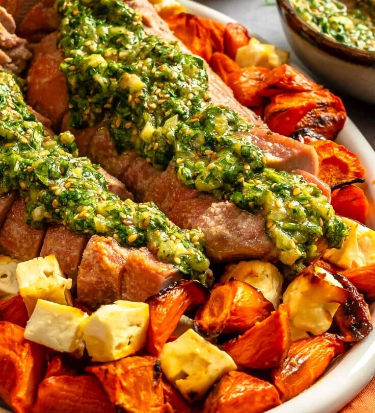 Sliced pork topped with green herb sauce, served with roasted carrots and cubed feta.