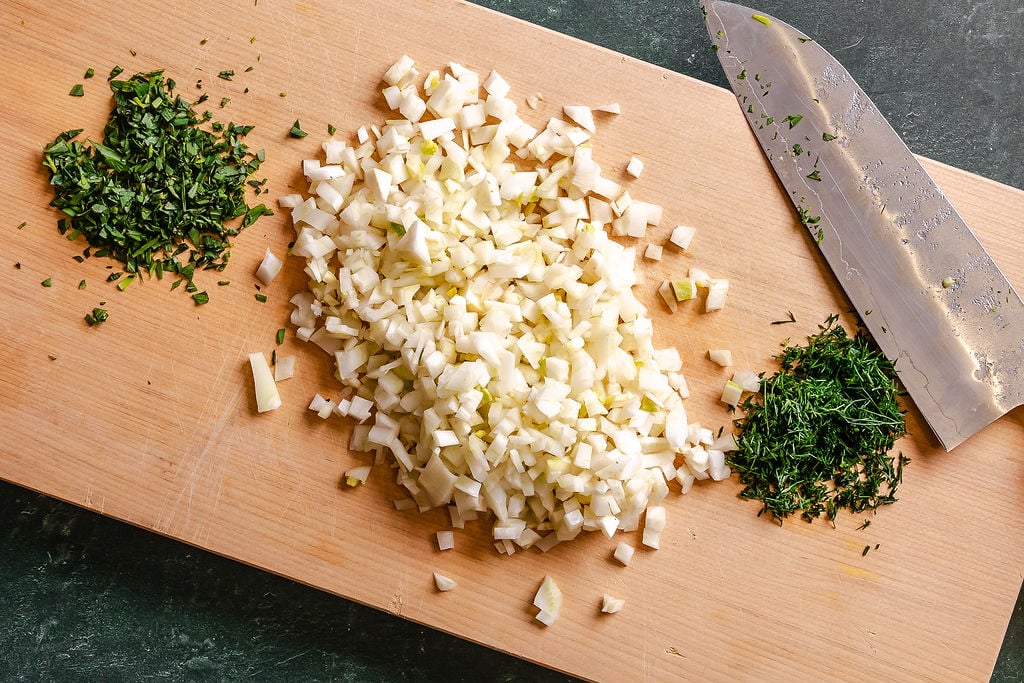 Diced fennel bulb and fronds on a wood cutting board.