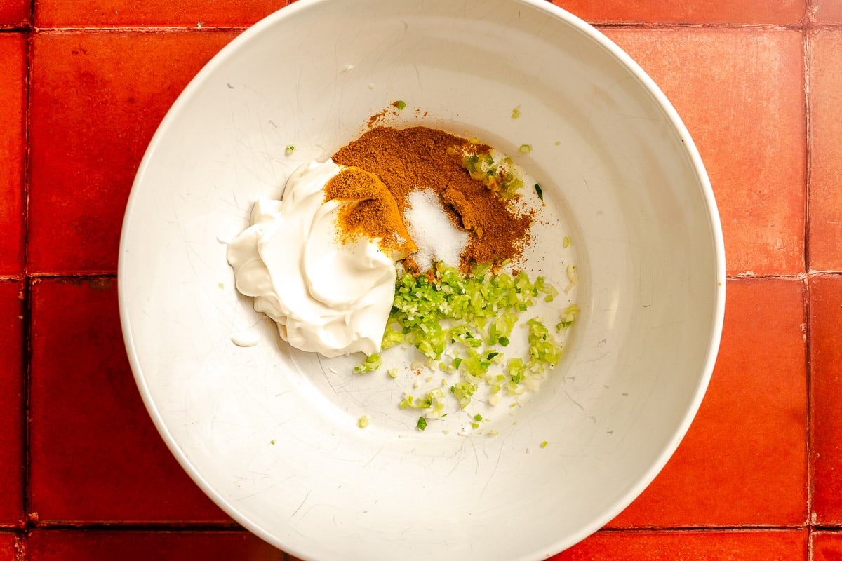 Mayonnaise, curry powder and minced green onions in a large white mixing bowl.