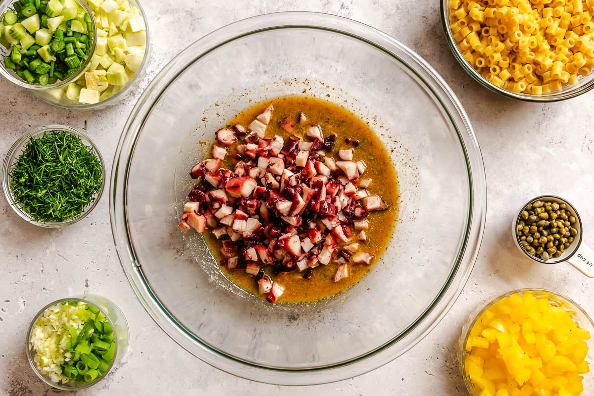 Diced octopus in a large bowl with a vinaigrette.
