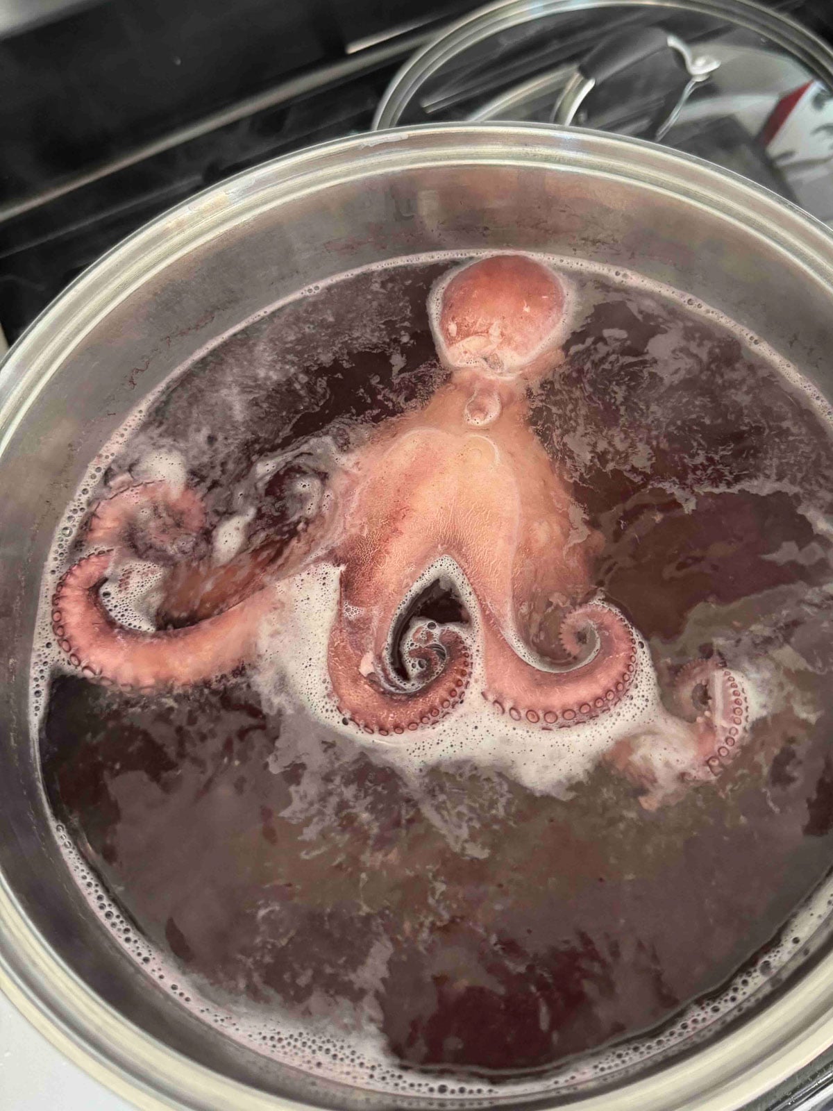 Whole octopus simmering in a pot of water.