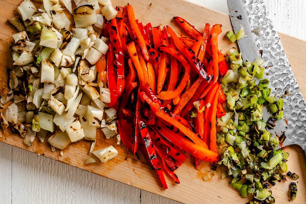 Diced grilled fennel, sliced grilled red bell pepper, and minced grilled scallions on a wood cutting board.