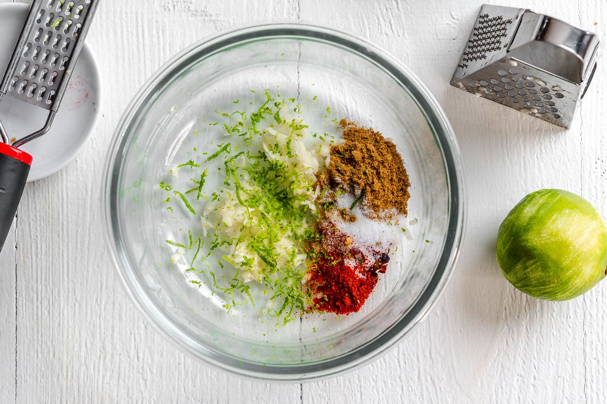 Lime zest, cumin, salt, and grated garlic in a glass bowl.