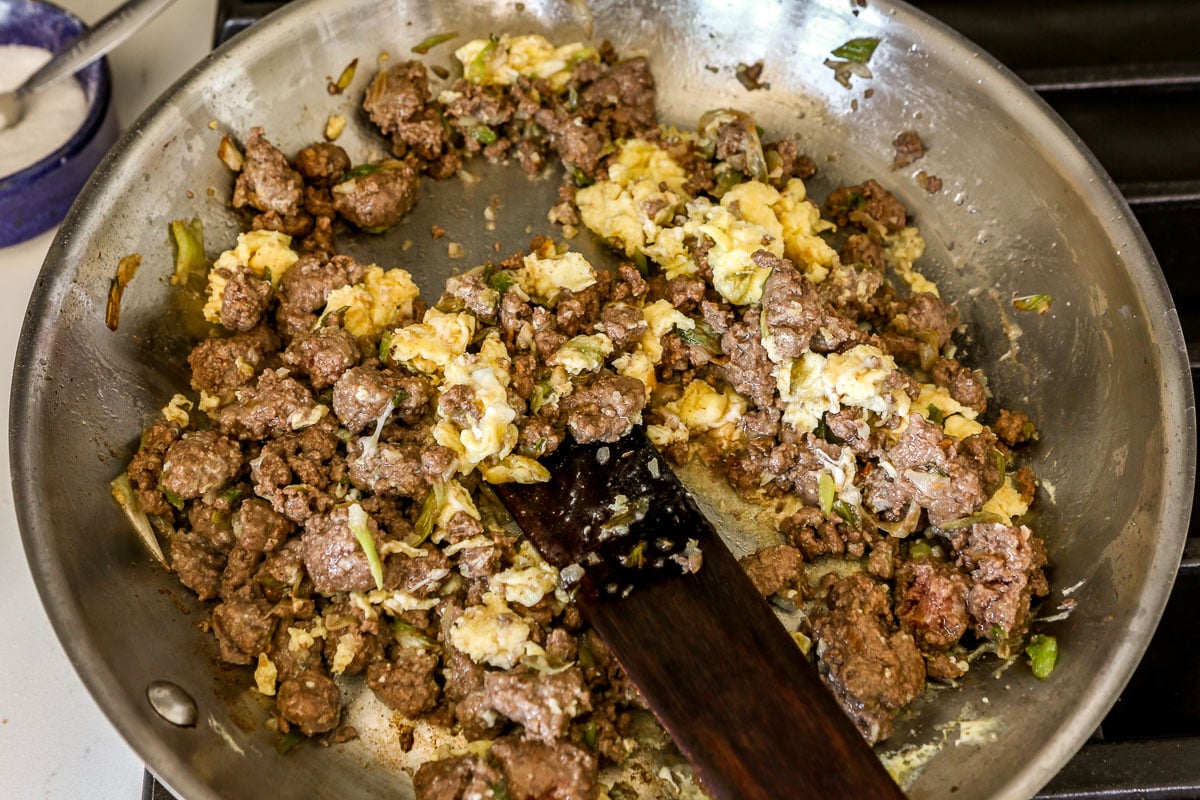 Cooked ground beef and scrambled eggs in a large stainless steel skillet.