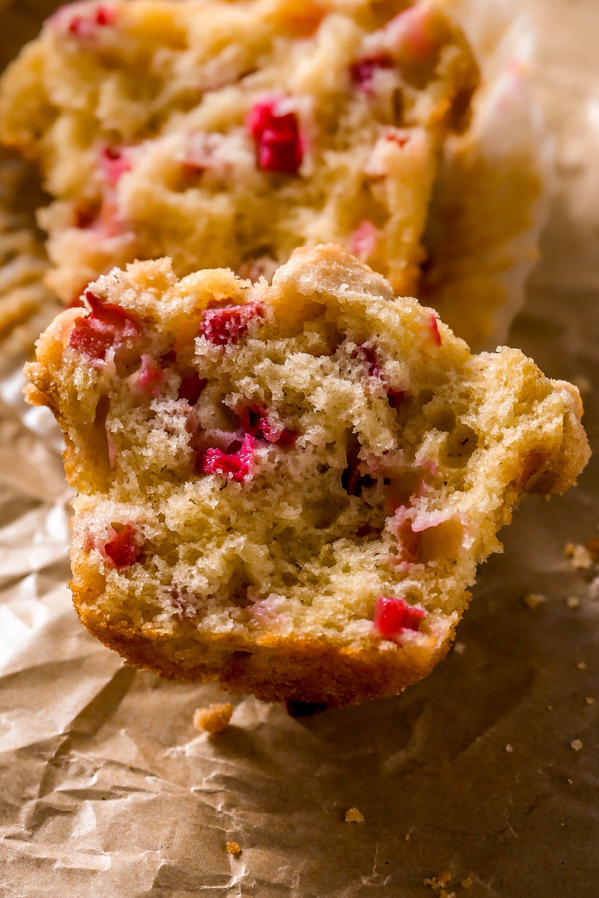 A close-up of the inside of a rhubarb muffin on brown parchment paper.