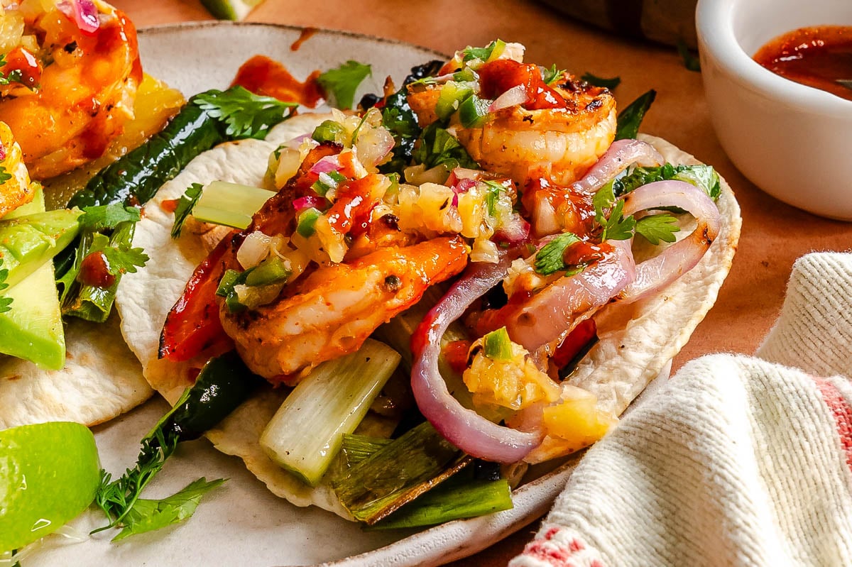 Two flour tortillas filled with shrimp fajita makings featuring grilled peppers, pineapple and a salsa