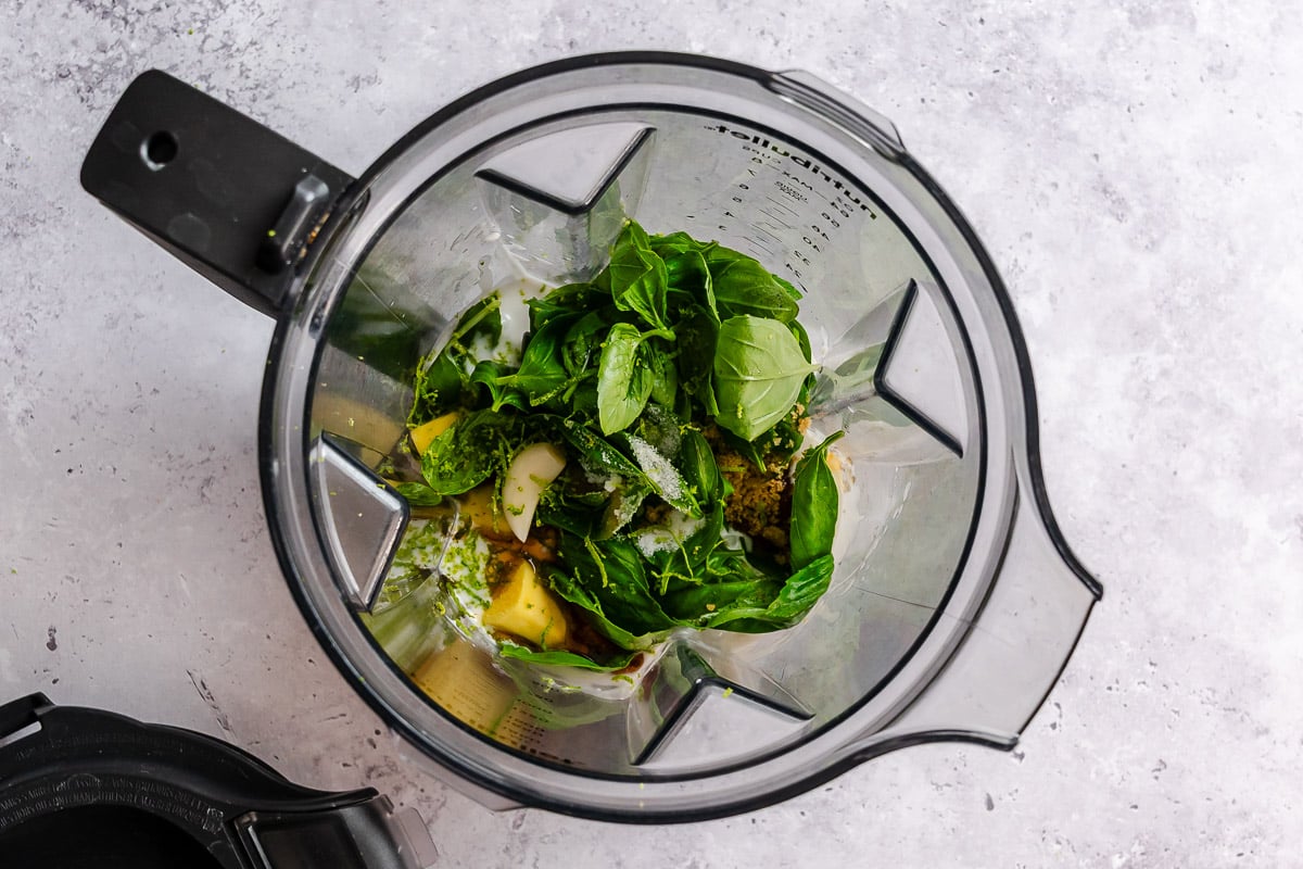 Basil, ginger, lime zest, brown sugar, toasted sesame oil, garlic, and coconut milk in a blender getting ready to blend into a sauce.