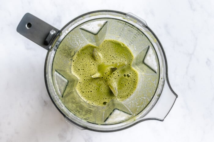 Overhead view of a blender with a blended green sauce in it for aguachile.