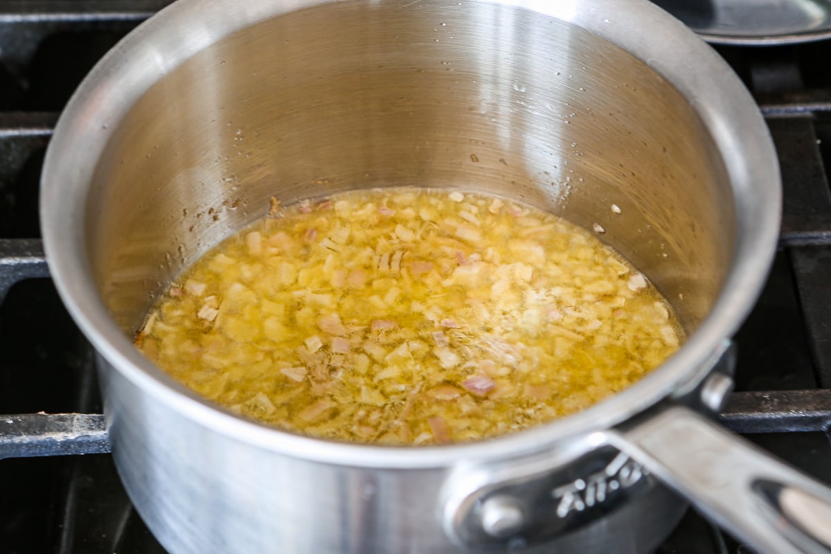 Diced shallots cooking in oil in a saucepan.