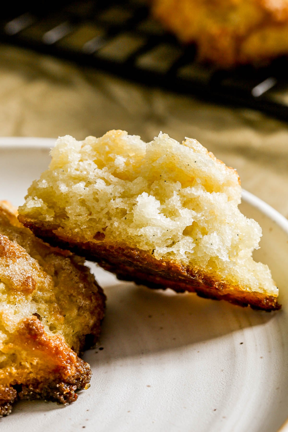 A close-up of a golden, crumbly scone broken open on a white plate, showing its fluffy inside.
