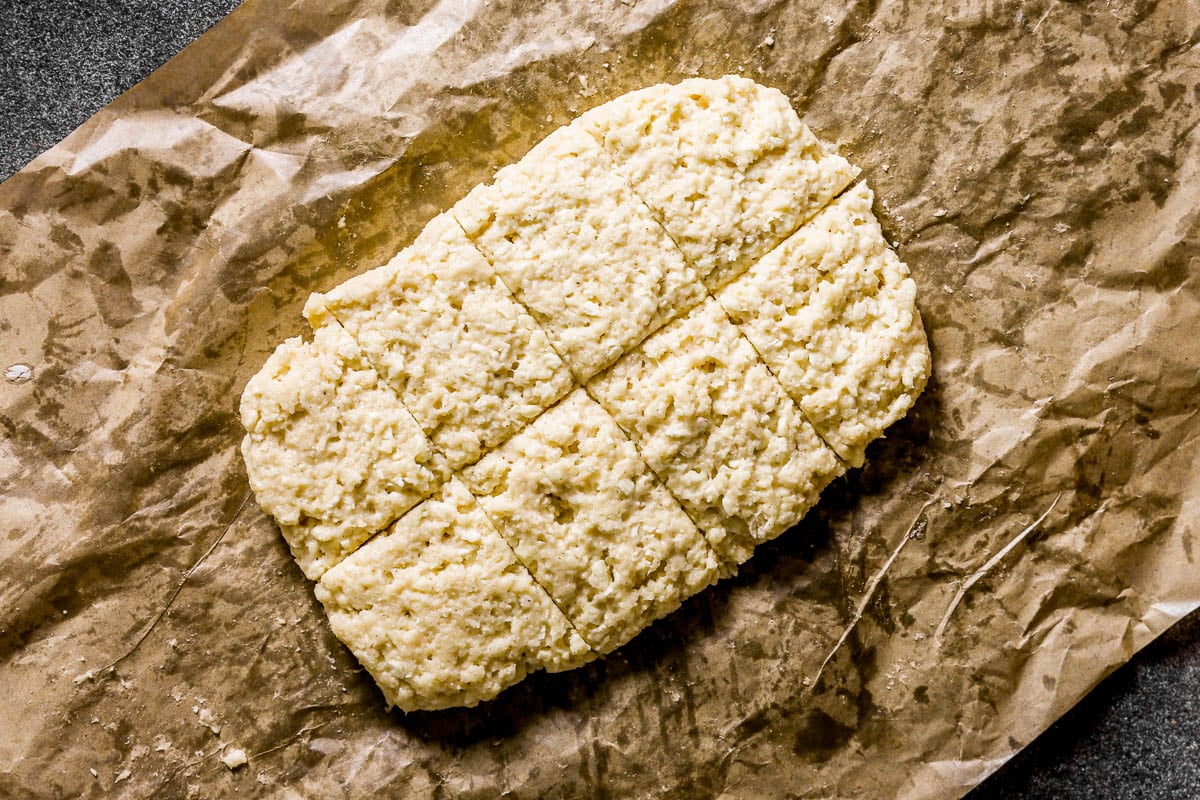 Rectangular block of dough, scored into squares, placed on crumpled brown parchment paper.
