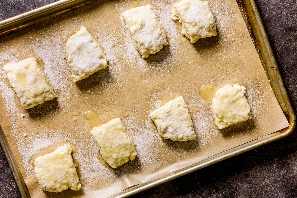 Eight unbaked, sugar-coated scones on a parchment-lined baking sheet, ready for the oven.