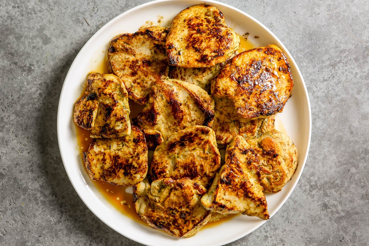 Pan-seared chicken breasts arranged on a white plate.
