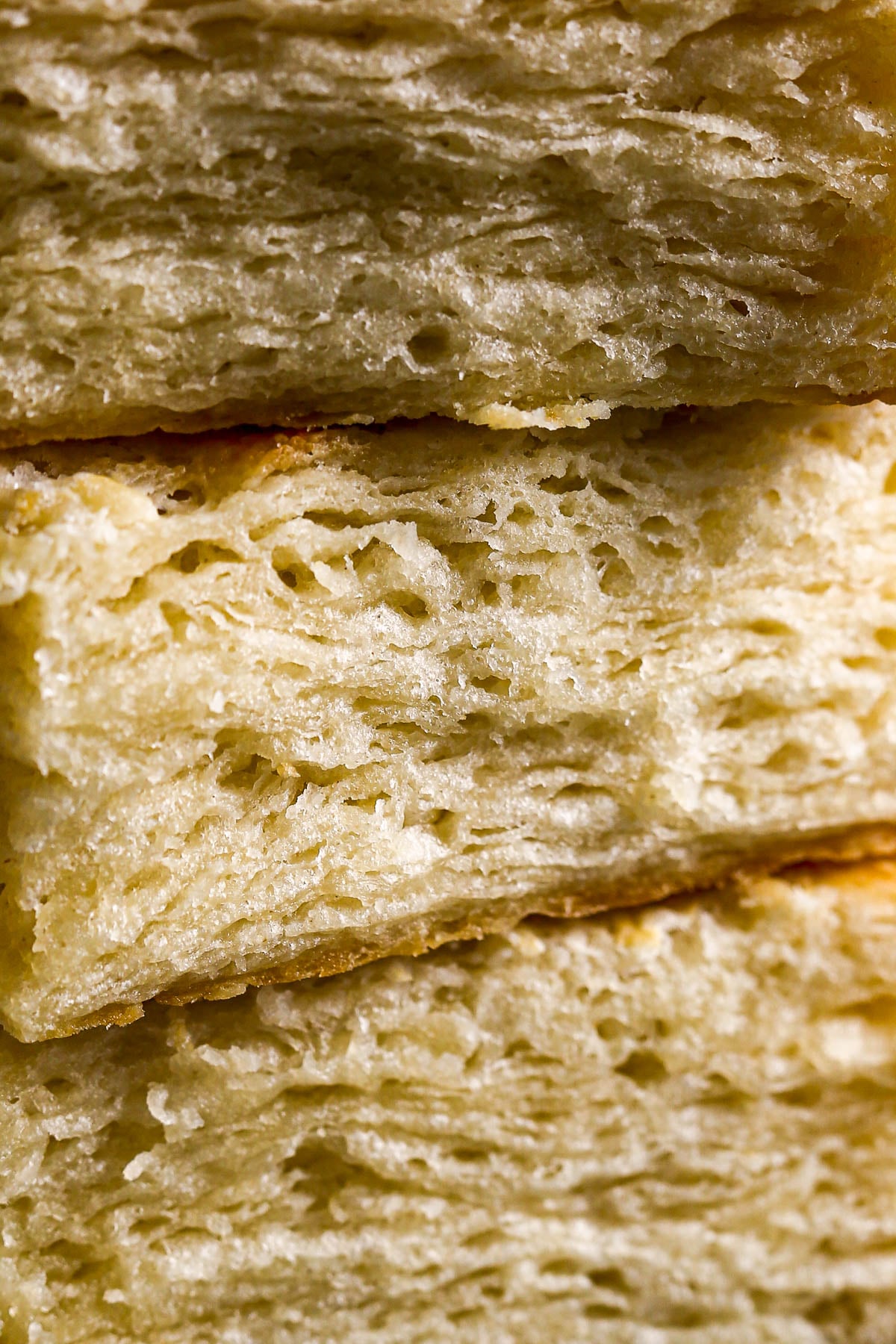 Close-up of flaky, golden layers of buttermilk biscuits, showing detailed texture and light, airy crumb.