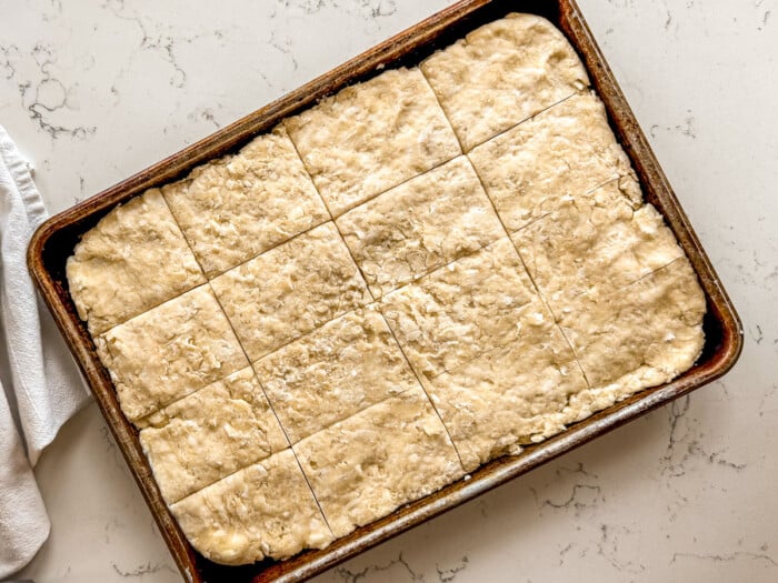 Biscuit dough pressed into a sheetpan and cut into squares.