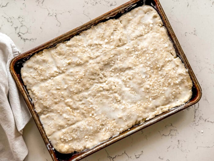 Sheet pan of unbaked biscuit dough brushed with buttermilk and sprinkled with flaky sea salt.