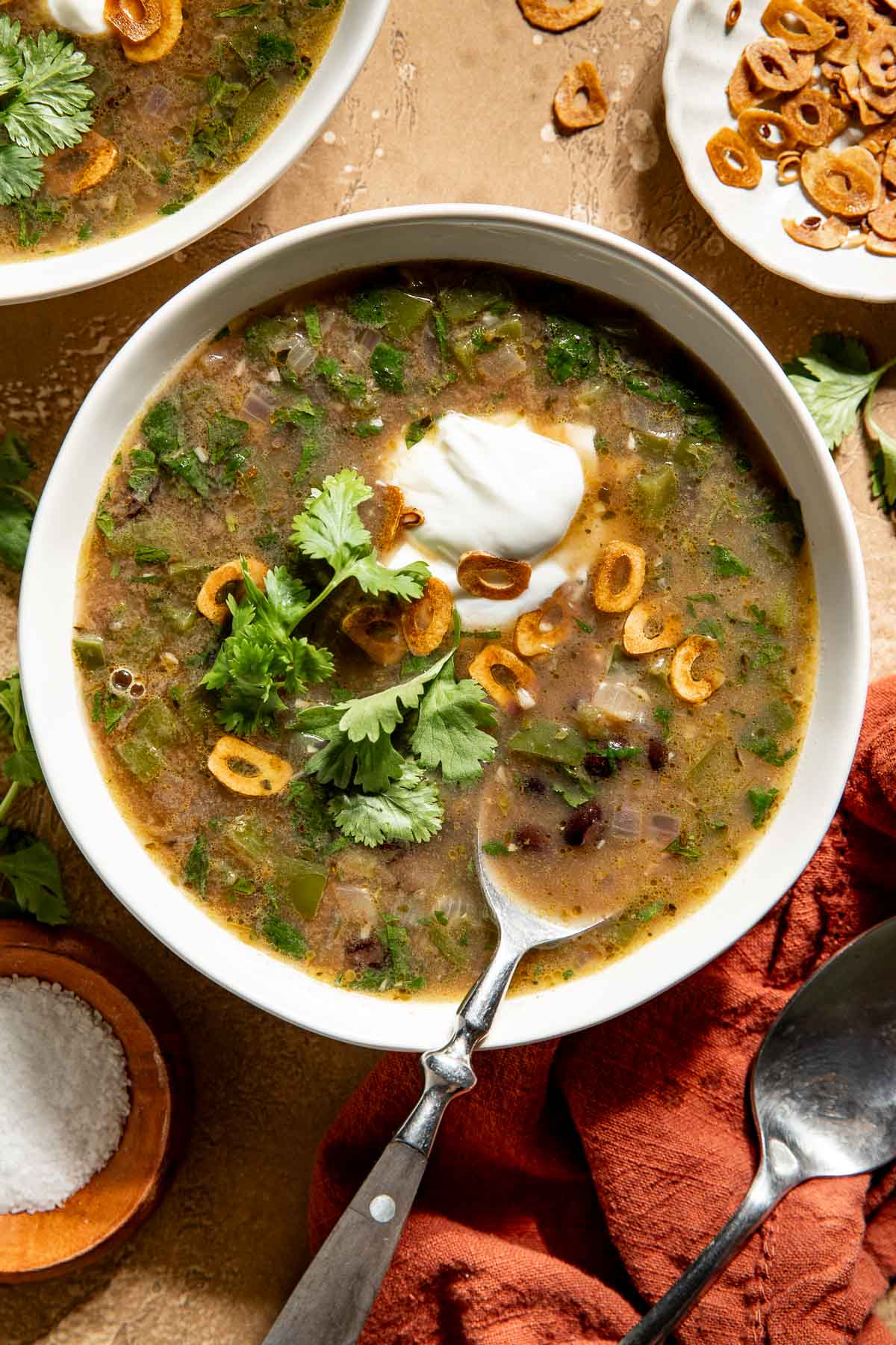 A bowl of black bean soup topped with Greek yogurt, cilantro, and fried garlic.