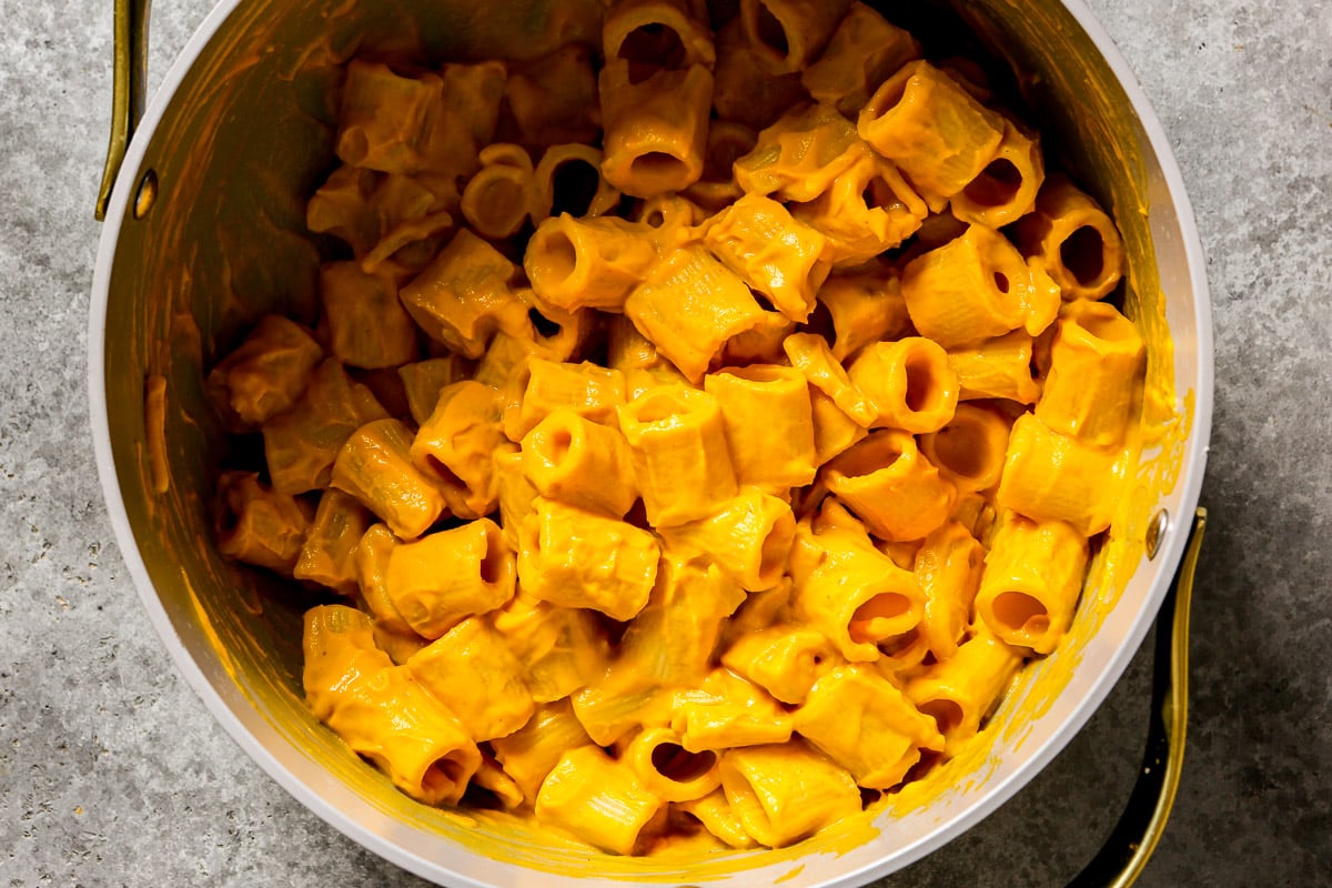 Rigatoni pasta tossed in a creamy pumpkin sauce in a metal pot.