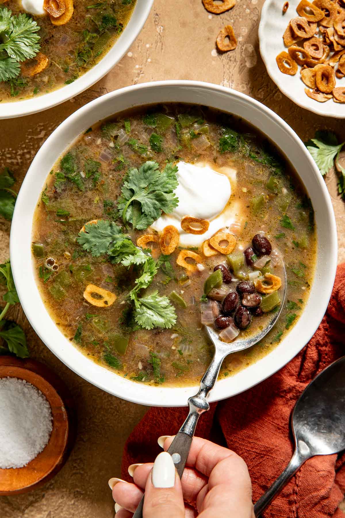 A bowl of black bean soup topped with Greek yogurt, cilantro, and fried garlic.
