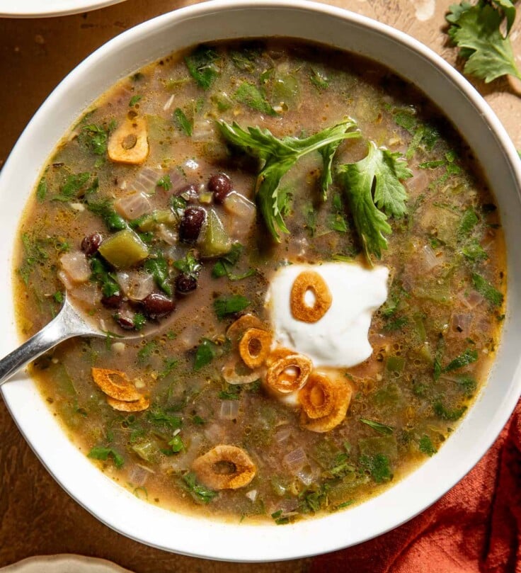 A bowl of black bean soup topped with Greek yogurt, cilantro, and fried garlic.