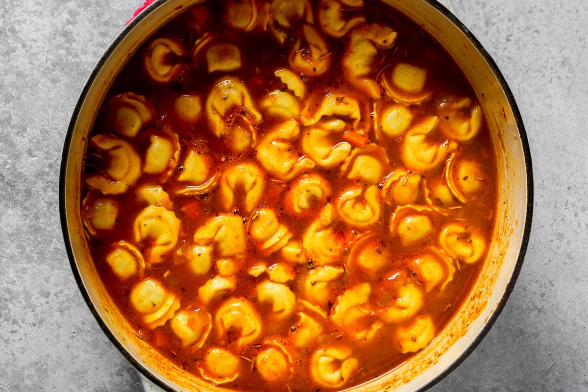 A pot of tomato-based tortellini soup.
